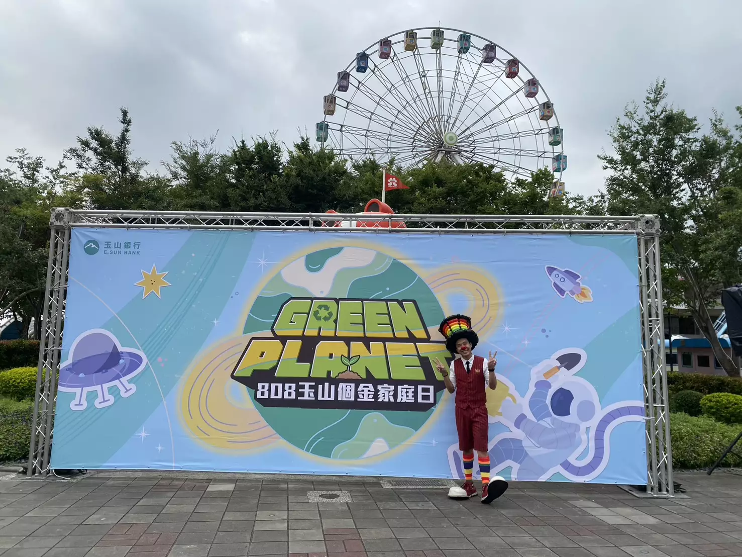 氣球大叔站在兒童新樂園摩天輪前方合影，展現家庭日主題布景