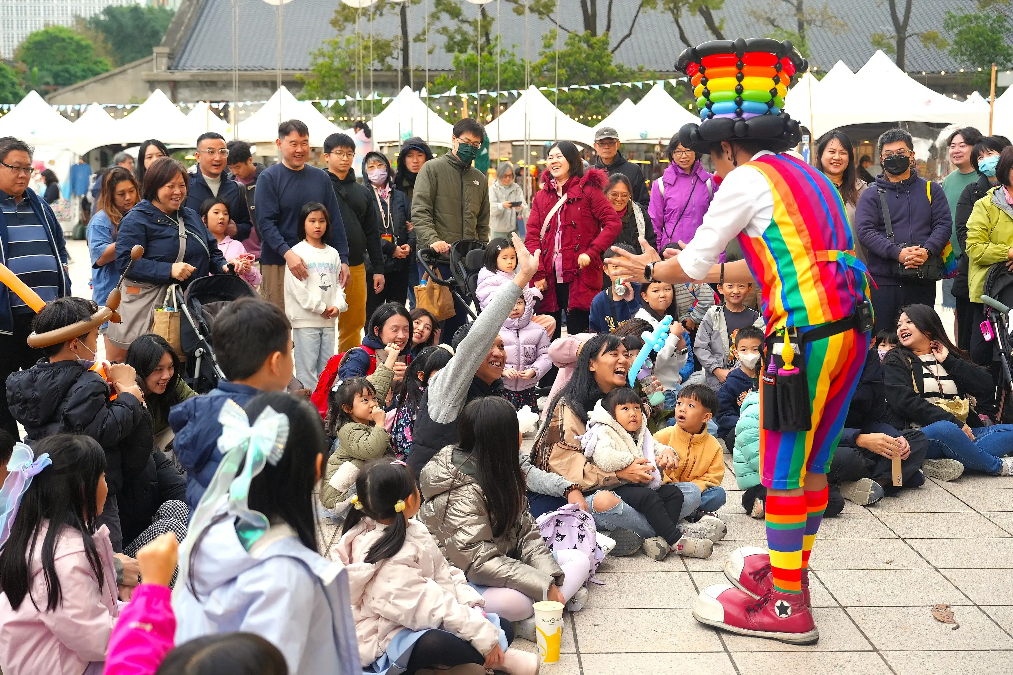 家庭親子在活動現場觀看氣球大叔 Sony 的氣球魔術秀，笑容燦爛