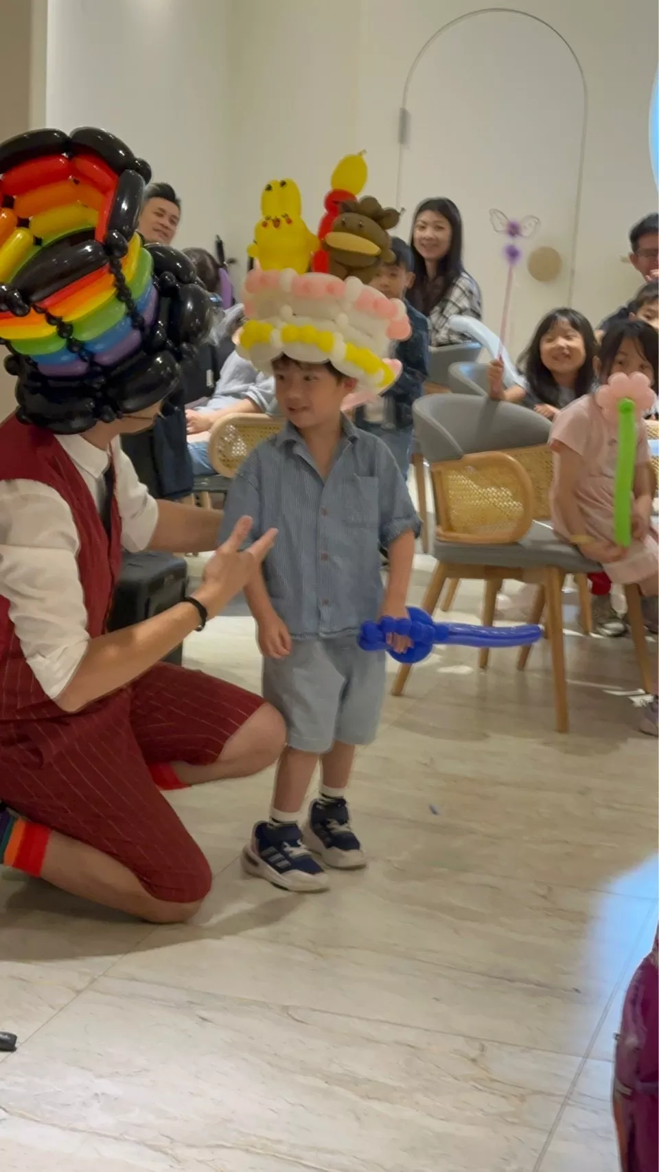 小朋友與氣球大叔互動合影，頭戴可愛氣球帽