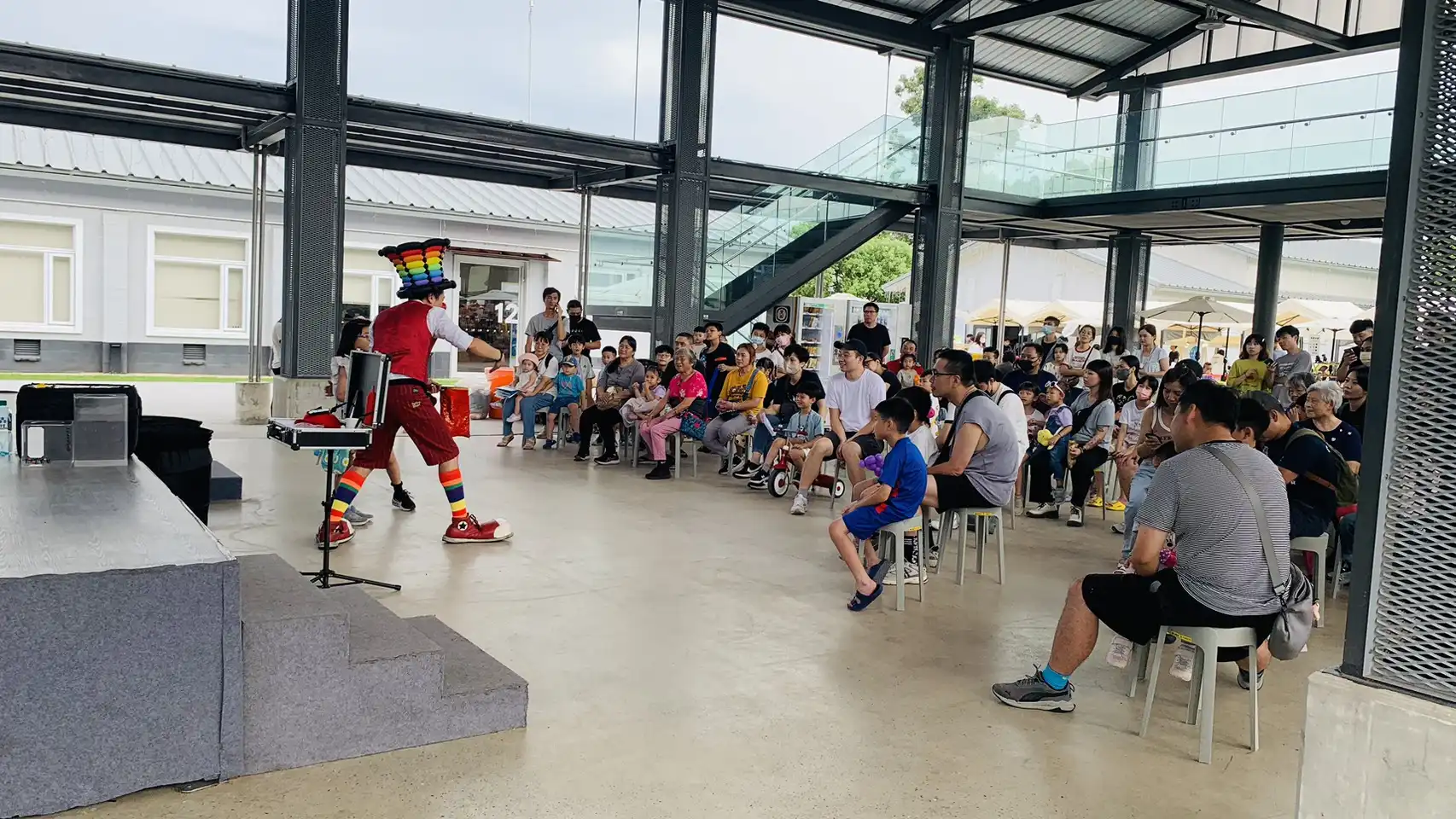 氣球大叔在桃園中原文創園區表演氣球魔術，觀眾席坐滿大小朋友，氣氛熱鬧